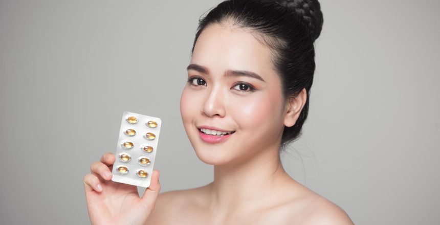 Young smiling asian woman with Omega 3 fish oil capsule